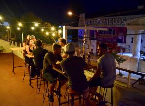 grupa ludzi siedzących przy stolikach w barze w nocy w obiekcie Central Paz Hostel w mieście Villa Carlos Paz