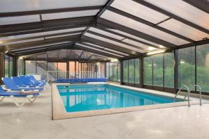 an indoor swimming pool with windows and blue chairs at Hotel Neuhauser in La Broque