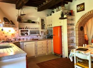 a kitchen with an orange refrigerator and white cabinets at Haus Malerin mit Meerblick eingezäuntem Garten by ToscanaTour in Guardistallo