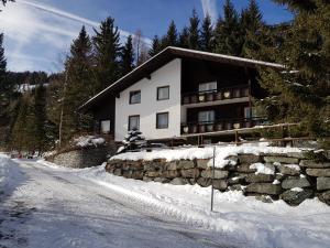 a house in the snow with a stone wall at Der Kristall by Globalimmoservice in Bad Kleinkirchheim