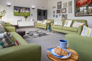 a living room with couches and a table with a plate of bread at West Point House in Barrow in Furness