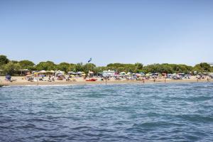a beach with umbrellas and a crowd of people at Italy Camping Village in Cavallino-Treporti