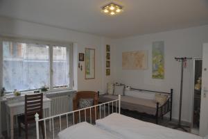 a bedroom with two beds and a desk and a window at Kiki's B&B in Basel