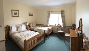 a bedroom with two beds and a desk and a window at O'Connors Guesthouse in Faha