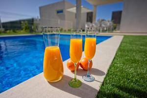 tres vasos de zumo de naranja sentados junto a una piscina en Villa Paradise, en Playa Paraiso