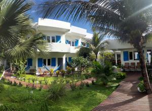 a large white house with palm trees in front of it at Pousada Caminho da Praia in Jericoacoara