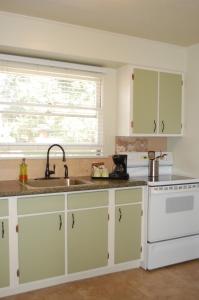 a kitchen with white cabinets and a sink at Trees Motel in Bishop