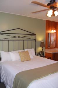 a bedroom with a large white bed with a ceiling fan at Trees Motel in Bishop