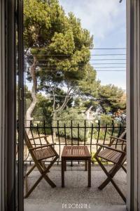 Duas cadeiras e uma mesa numa varanda com uma árvore em Bussana Forever, Sanremo Est em Sanremo