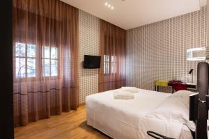 um quarto com uma cama branca e uma tv em Albergo Etico Roma em Roma