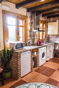 a kitchen with a microwave and a sink and a stove at Apartamentos Rurales Fuente Chiquita in Hervás