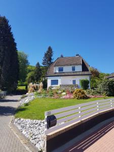 a white house with a fence in front of a yard at Ferienwohnung Villa am Golfplatz in Bad Harzburg