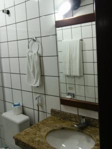 a bathroom with a sink and a mirror and a toilet at Taperapuan Praia Hotel in Porto Seguro