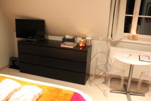 a bedroom with a dresser with a television and a table at B&B L'Orangerie in Waterloo