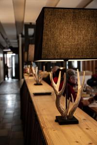 a table with a lamp with antlers on it at Hôtel Le Relais Alpin in Les Mosses
