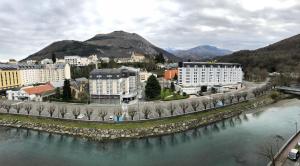 uma cidade ao lado de um rio com edifícios e montanhas em Hôtel Saint Georges em Lourdes