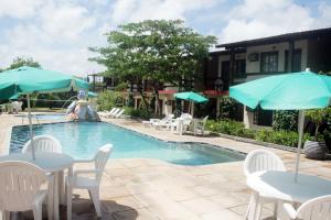 a pool with tables and chairs and umbrellas at Taperapuan Praia Hotel in Porto Seguro