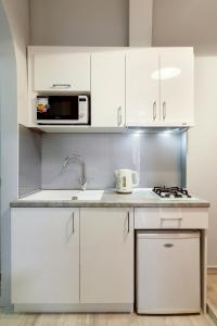 a white kitchen with a sink and a microwave at Queens Apartments 1 in Lviv