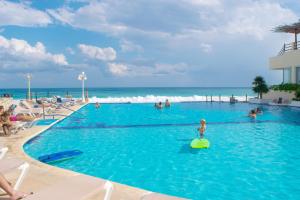 a swimming pool with people in the water and the ocean at BSEA Cancun Plaza Hotel in Cancún