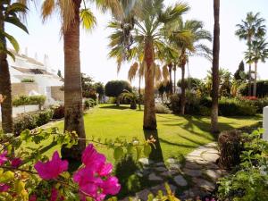 un jardín con palmeras y flores rosas en Apartament - dom, Hiszpania Andaluzja, Costa del Sol, en Estepona