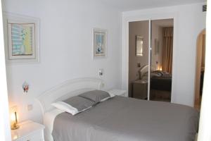 Habitación blanca con cama y espejo en Apartament - dom, Hiszpania Andaluzja, Costa del Sol, en Estepona