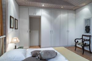 1 dormitorio con armarios blancos y 1 cama con silla en Art Deco Villa Mon Abri BnB, en Goldau