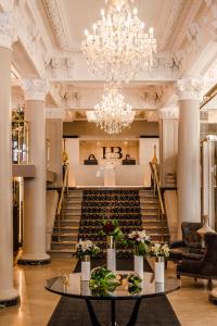 a lobby with a chandelier and a table with flowers at Hôtel Birks Montréal in Montreal