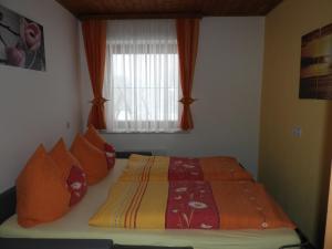 a bedroom with a bed with orange pillows and a window at Kleinwidmoos-Apartment in Wagrain