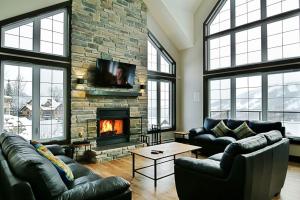 a living room with couches and a stone fireplace at Stonehamchalet21 in Stoneham