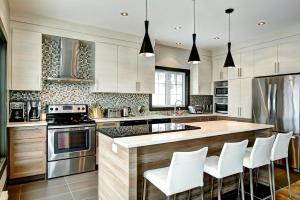 a kitchen with a counter with white chairs in it at Stonehamchalet21 in Stoneham