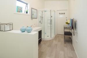 a white bathroom with a shower and a sink at Thistle Cottage in Ashburton