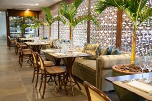 a restaurant with tables and chairs and palm trees at Hotel Florença in Americana