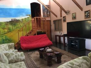 sala de estar con sofá rojo y TV en Hare Henua Bed & Breakfast, en Hanga Roa