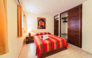 een slaapkamer met een bed met een rood en geel gestreepte deken bij Hotel Las Palmeras in Sosúa