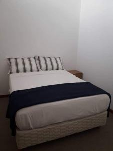 Duplex en Valle Hermoso في فالي هيرموسو: سرير أبيض مع بطانية ووسائد زرقاء