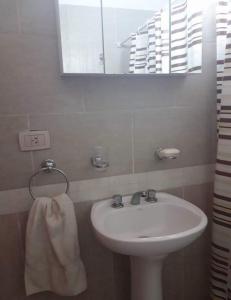 Duplex en Valle Hermoso في فالي هيرموسو: حمام مع حوض ومرآة ومنشفة