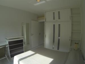 Habitación blanca con cama y armario en Bem localizado com sacada, churrasqueira, garagem e split, en Florianópolis