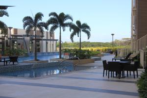 a table and chairs next to a swimming pool with palm trees at Marquee Residences in Angeles