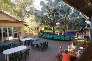 a group of people sitting at tables in a patio at Red Rock Hostel in Alice Springs