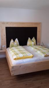un letto in legno con due cuscini sopra di Ferienwohnung Tobias a Zell am Ziller