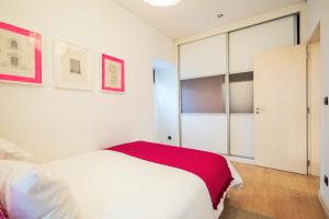 um quarto com uma cama branca e um cobertor vermelho em Casa da Praceta em Lisboa