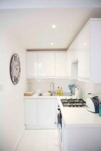 a kitchen with white cabinets and a clock on the wall at Beautiful one Bedroom apartment walking distance to Paddington and Hyde Park in London