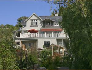 a large white house with a balcony and an umbrella at Joya Garden & Villa Studios in Nelson