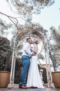 uma noiva e um noivo a beijarem-se debaixo de um arco no seu casamento. em Casa Toscana Lodge em Pretoria