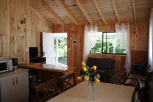 Una habitación con una mesa con un jarrón de flores. en Cabañas Don Vittorio, en Caburgua