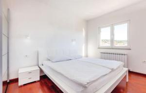 a white bedroom with a large bed and a window at Apartments Host in Rab