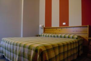 a bedroom with a bed with a plaid blanket on it at Hotel Valdotain in Villeneuve