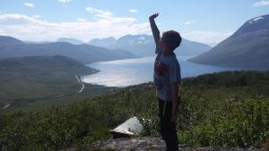 a young boy standing on a rock with his arm in the air at Utsikten Feriehus i Bakkeby in Bakkeby