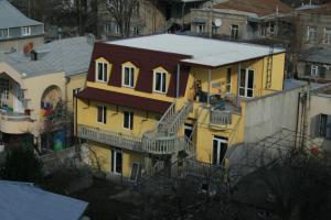 una casa gialla con una scala sul lato di Why Me Eco-friendly Hostel a Tbilisi City