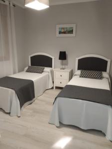 um quarto com 2 camas e uma cómoda com um candeeiro em Mareventus em Sanxenxo